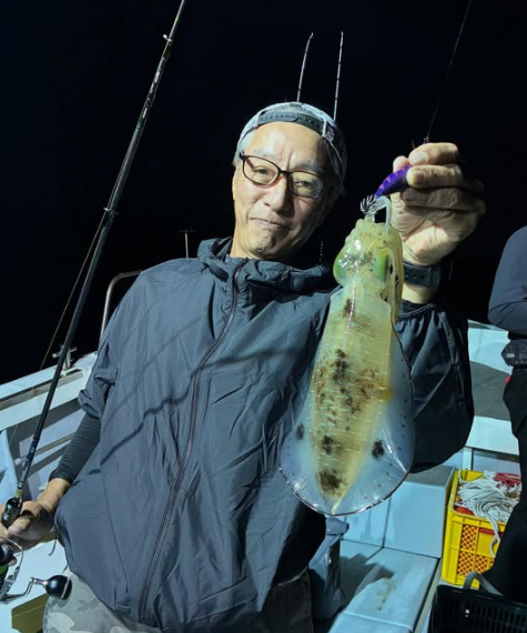 新晴丸の船上からティップランでアオリイカを釣り上げたお客様。鳥取の夜の海で、価値ある一杯を手に記念写真。