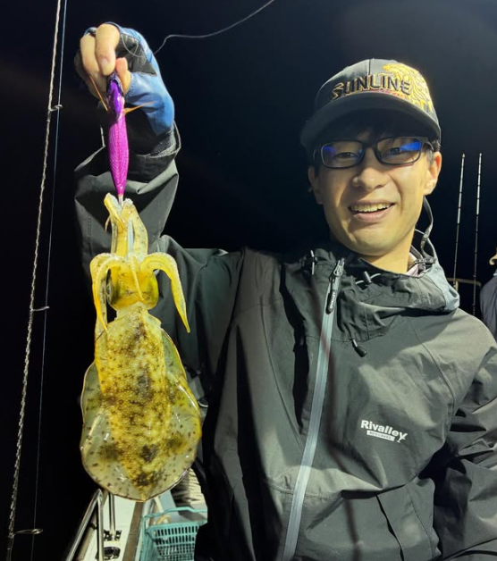 鳥取のティップランでアオリイ-カをゲット。サンラインのキャップを被ったお客様が、紫色のエギで釣れた一杯を手にニッコリ。