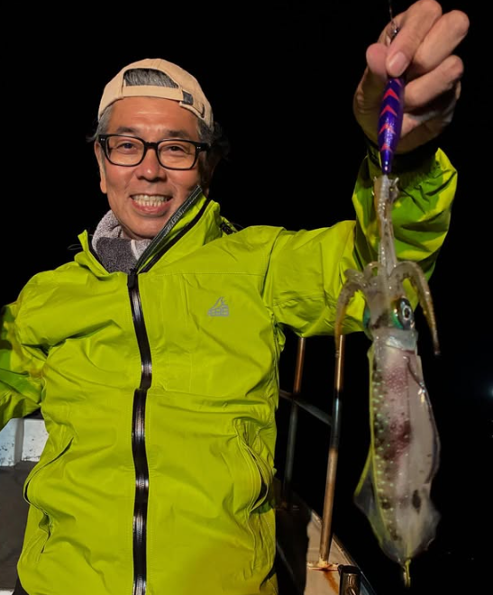 鳥取のティップランで釣り上げたアオリイカ。黄緑色のウェアを着たお客様が、嬉しい釣果を手に笑顔でポーズ。