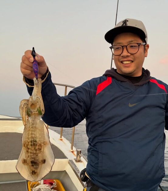 鳥取でのティップラン釣行。お客様が釣り上げたアオリイカを手に、満足そうな笑顔で記念撮影。