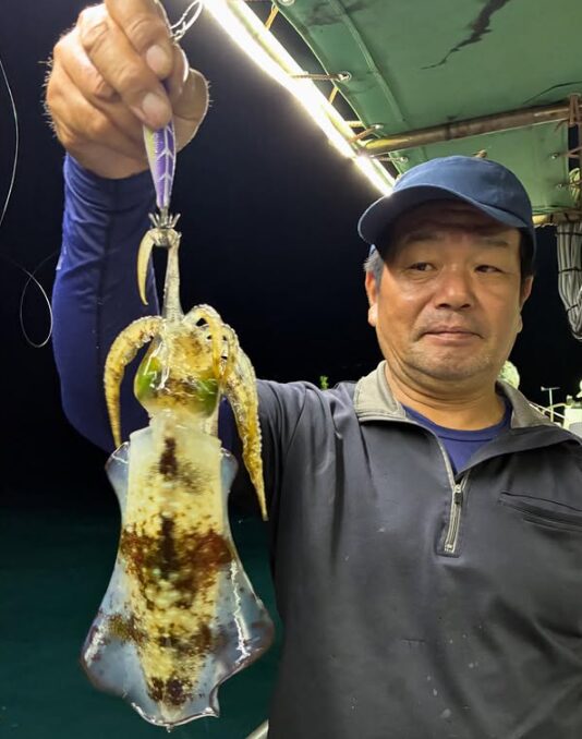 鳥取でのティップラン釣行。お客様が釣り上げたアオリイカを手に、カメラを見つめる一枚。