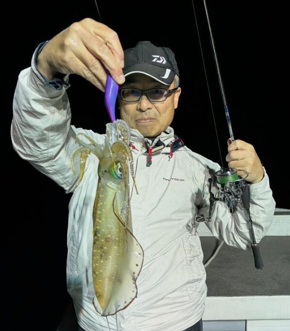 鳥取でのティップラン釣行。お客様が釣り上げたアオリイカを手に、カメラを見つめる一枚。