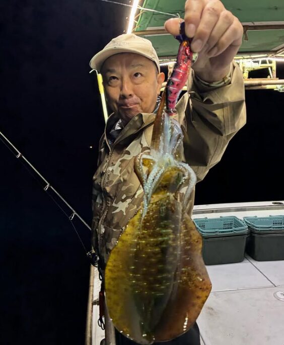新晴丸のティップランでアオリイカをキャッチ!迷彩柄のジャケットを着たお客様が、鳥取の海で釣り上げた一杯を披露。