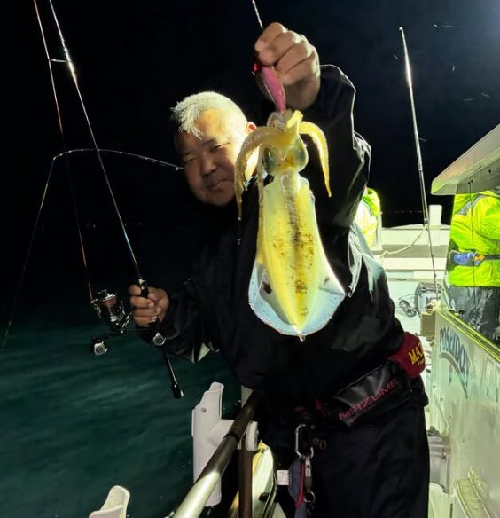 鳥取のティップランでアオリイカを釣り上げたお客様。夜の海で、価値ある一杯を手に記念撮影。