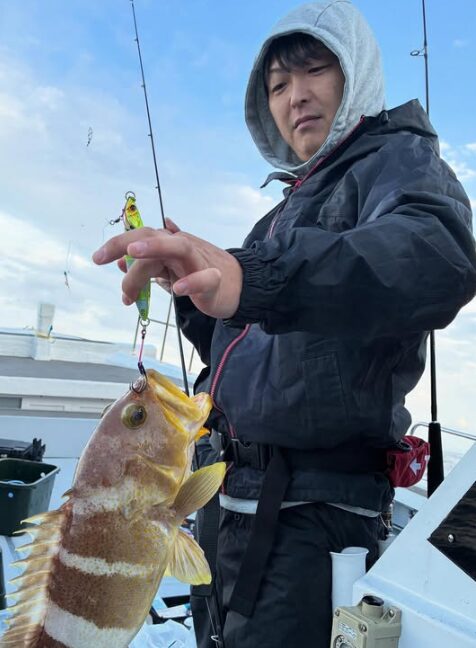 鳥取の遊漁船「新晴丸」でのジギング釣果。お客様が、ヒットしたアオハタをフックから外している瞬間。