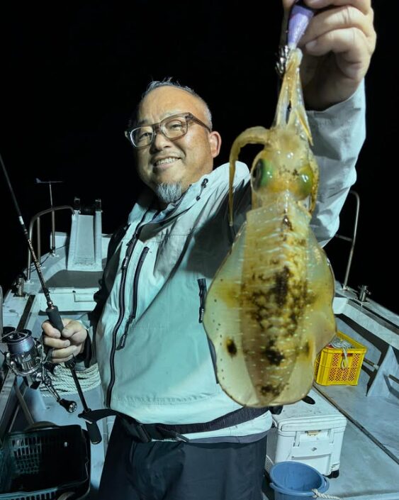 鳥取でのティップラン釣行にて、良型のアオリイカをゲット!グレーのウェアを着たお客様が、嬉しい釣果を手に記念撮影。