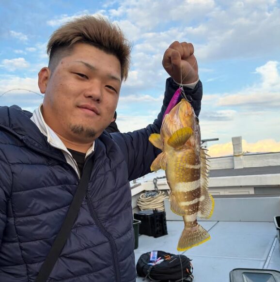 鳥取の遊漁船「新晴丸」でのジギング釣果。お客様が、紫色のジグで釣り上げたアオハタを手にニッコリ。