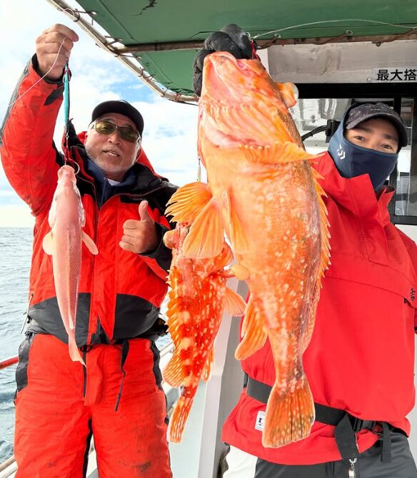 鳥取の遊漁船でのジギング釣果。赤いウェアを着た釣り人2名が、大きなアコウ（キジハタ）やカサゴ、アマダイといった見事な根魚を手に笑顔で掲げている。