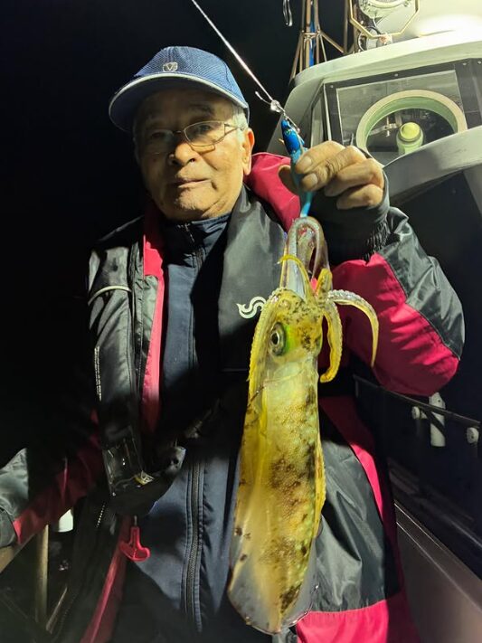 鳥取のアオリイカティップランにて、ピンクのラインが入ったジャケットと青いキャップのお客様が、青系のエギでキャッチした様子