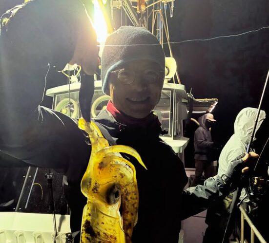 境港遊漁船の夜便にて。重見プロが、ティップランでキャッチしたキロアップと思われる巨大なアオリイカをエギごと持ち上げている様子。