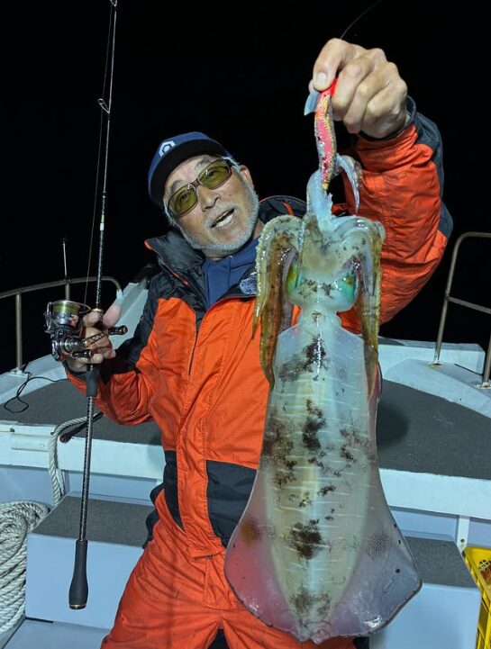 境港遊漁船の夜便にて。重見プロが、ティップランでキャッチしたキロアップと思われる巨大なアオリイカをエギごと持ち上げている様子。