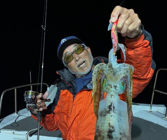 境港遊漁船の夜便にて。重見プロが、ティップランでキャッチしたキロアップと思われる巨大なアオリイカをエギごと持ち上げている様子。