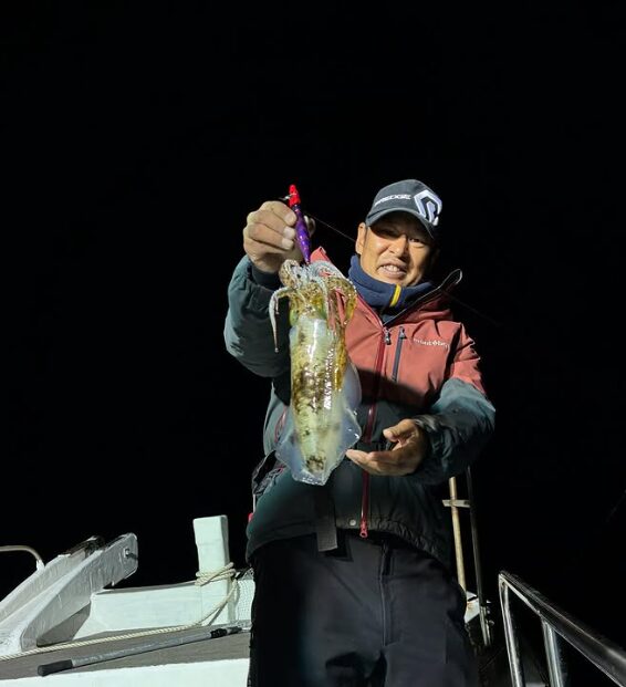 鳥取の釣り船にて、夜のティップランで良型のアオリイカを釣り上げ、笑顔を見せる