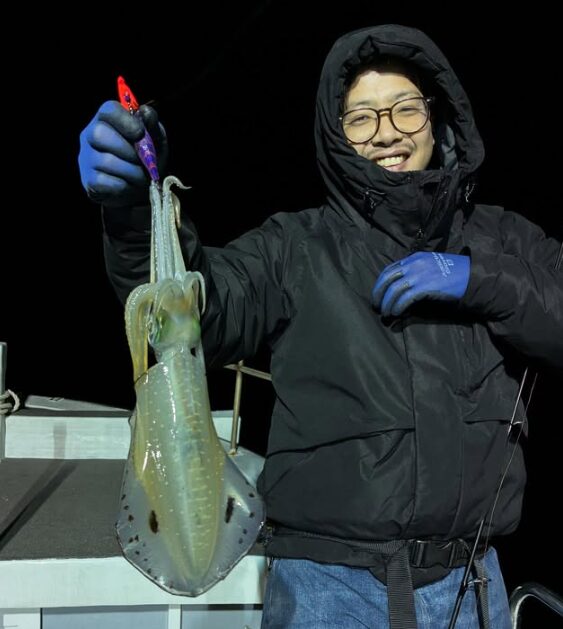 鳥取でのティップランで釣り上げたアオリイカ。フードを被ったお客様が、貴重な釣果を手に笑顔。