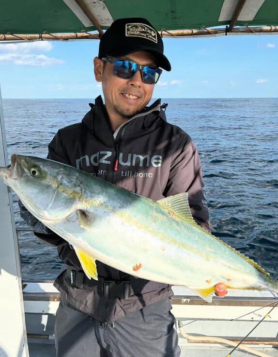 鳥取の釣り船にて、ジギングで釣り上げた立派なヒラマサを手に笑顔のお客様。